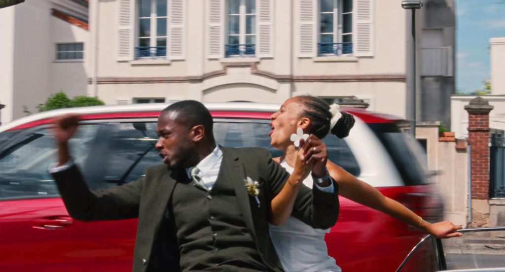 Dao_nyff64_01-scaledjpeg | the Cinema Group Couple in a Wedding Outfit Riding in a Red Convertible, Celebrating with Hands Raised.
