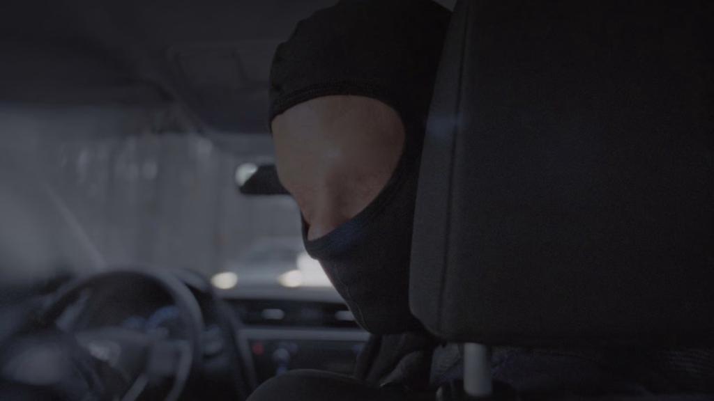 Heil-jupiter-_nyff64_01jpg | the Cinema Group Hooded Person Wearing a Mask Sits in the Backseat of a Dark Car, Low Light and Dashboard Visible in the Foreground.