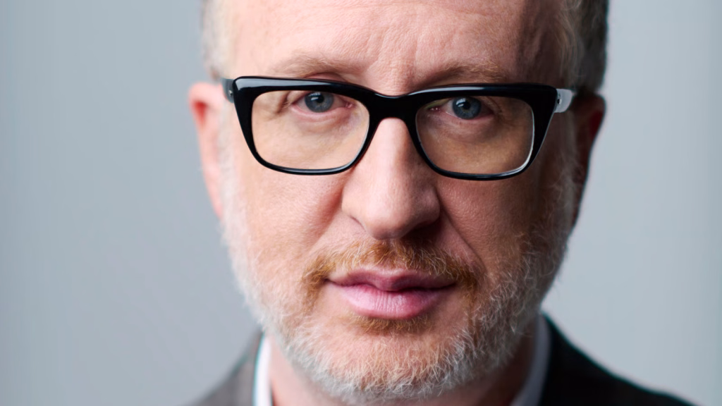 Talks_james-graypng | the Cinema Group Close-up of a Middle-aged Man with Gray Beard and Black-framed Glasses Looking into the Camera.