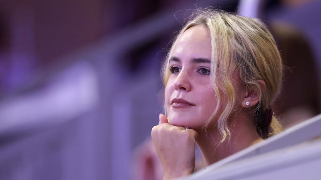 Woman with Blonde Hair Rests Her Chin on Her Hand, Looking Thoughtful in a Purple-lit Setting.