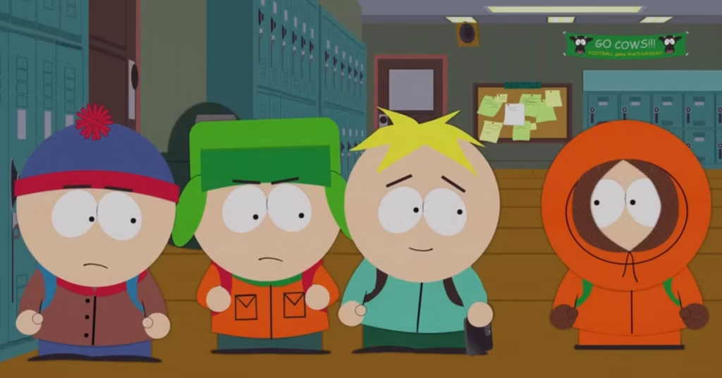 Four Kids in a School Hallway with Blue Lockers: Stan in a Blue Hat, Kyle in a Green Hat, Cartman with Blond Hair, and Kenny in an Orange Hooded Jacket.