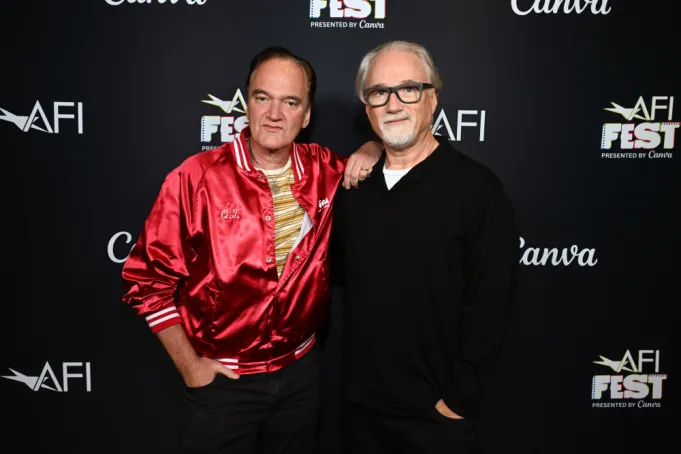 2301724953jpg | the Cinema Group Two Men Posing Together on the Afi Fest Red Carpet, One in a Red Satin Jacket and the Other in a Black Shirt, Against a Branded Backdrop with Event Logos.