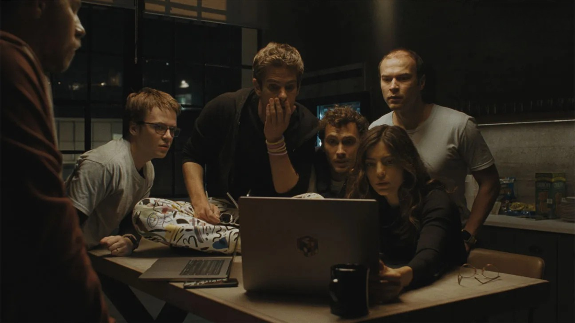 Aftiifical Frist Reactions Nyff the Cinema Group | the Cinema Group Five Young Adults Huddle Around a Laptop on a Dimly Lit Table, Absorbed in the Screen.