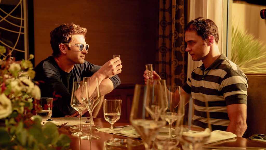 Artificial-neonjpg | the Cinema Group Two Men at a Warmly Lit Dining Table Toast with Glasses of Champagne, Surrounded by Wine Glasses and Plates in a Restaurant Setting.