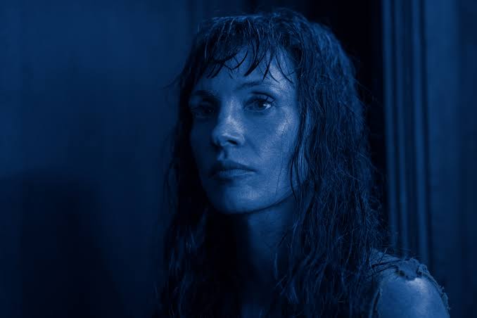 Portrait of a Woman with Wet Hair Looking Solemnly at the Camera in Blue-tinted Lighting.
